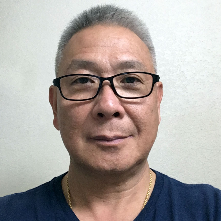 A man with short white hair, wearing a blue t-shirt and glasses